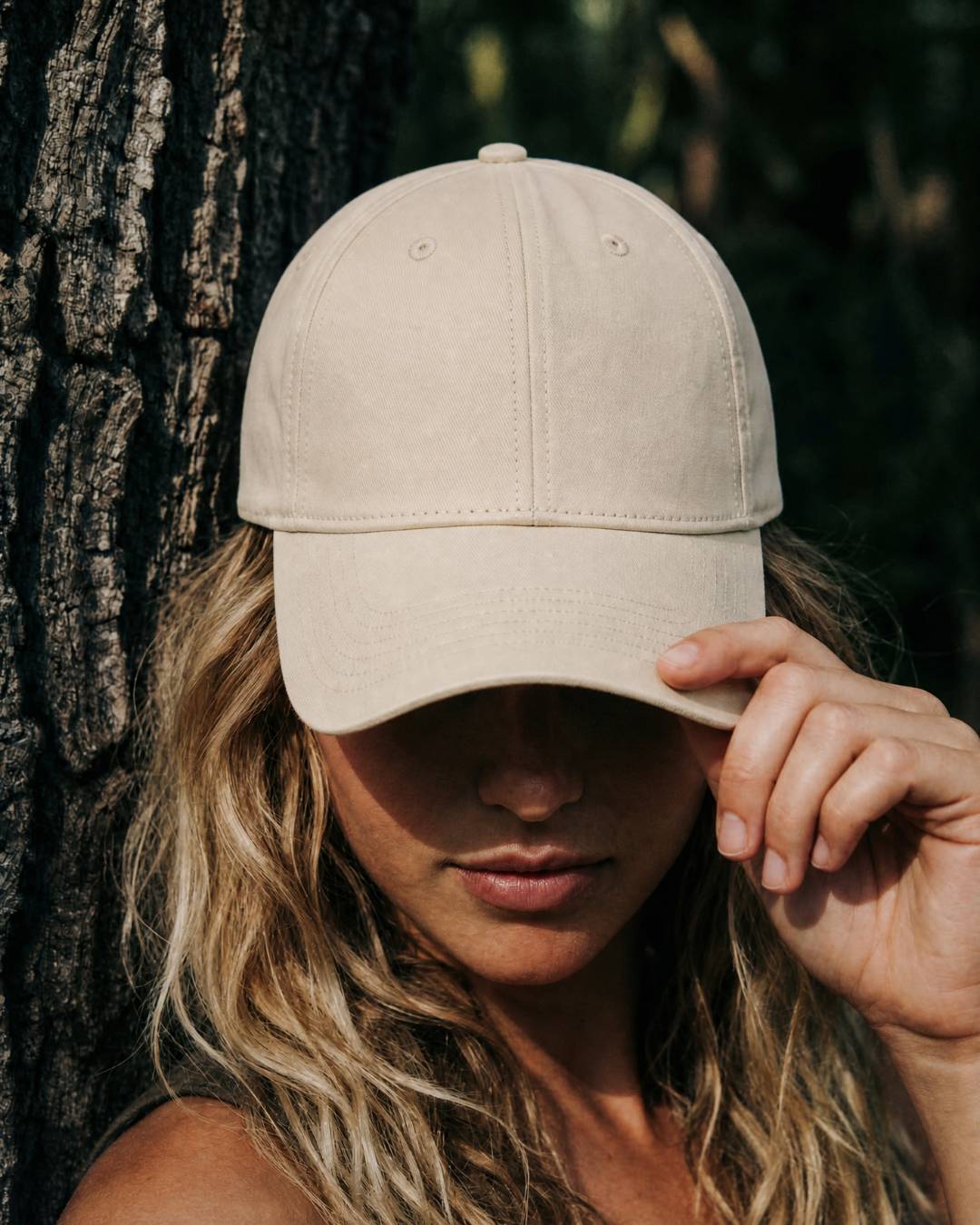 Person wearing a beige cap against a natural background