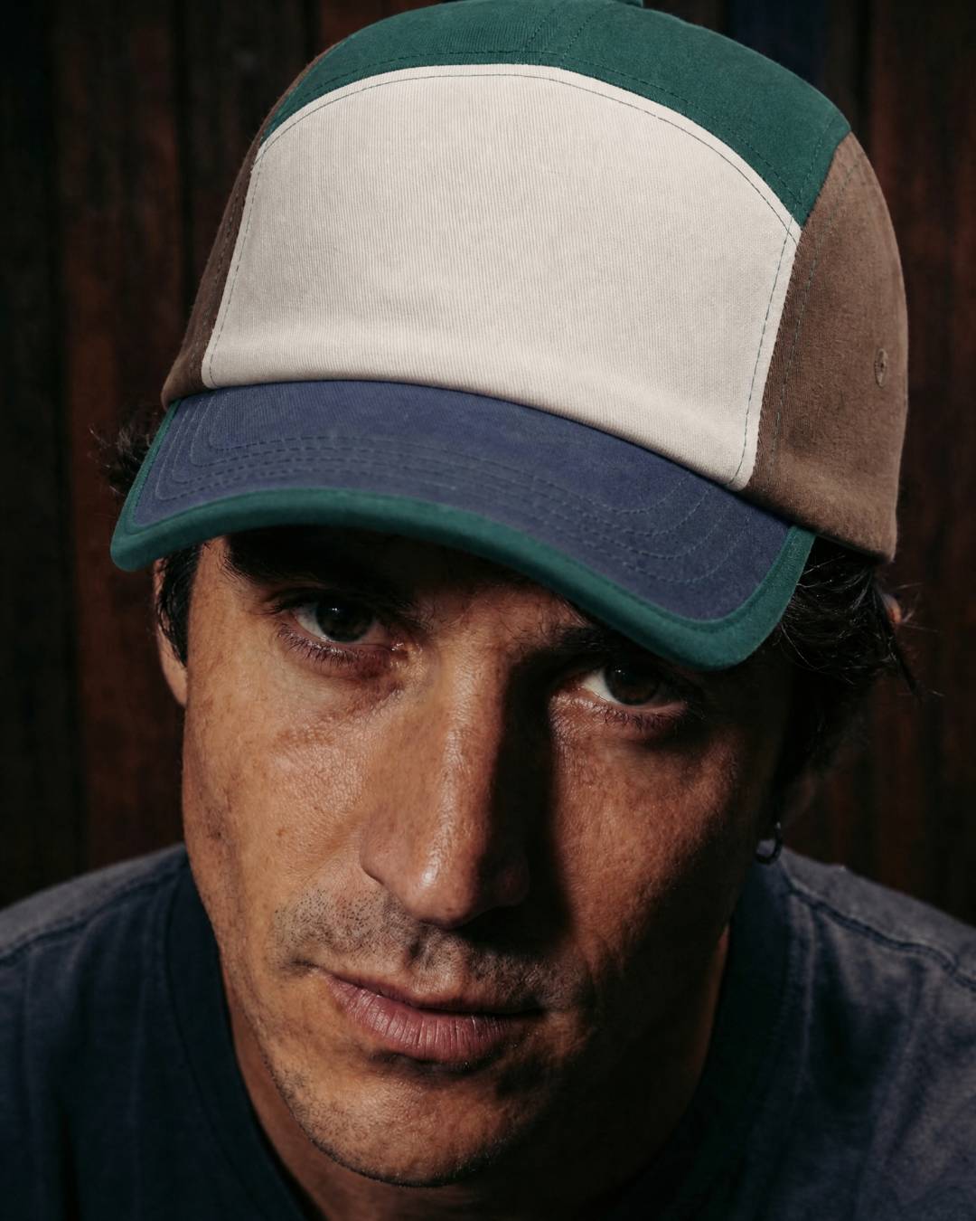 Man wearing a three-tone cap with a dark background