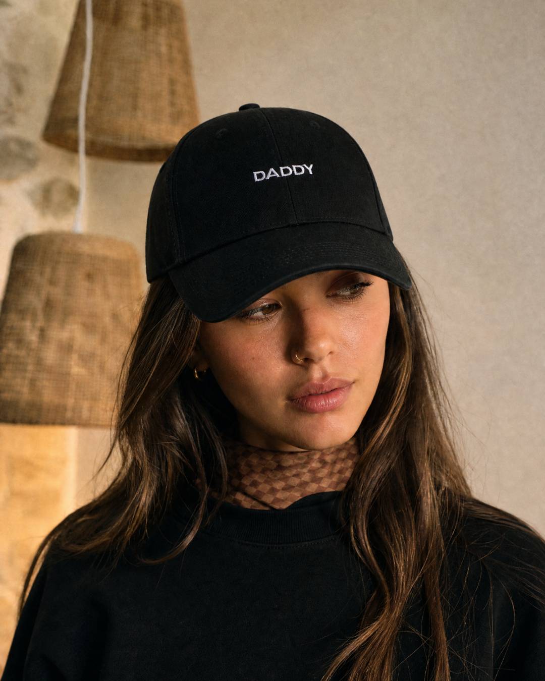 Person wearing a black cap with 'DADDY' embroidered on it, standing against a neutral background.