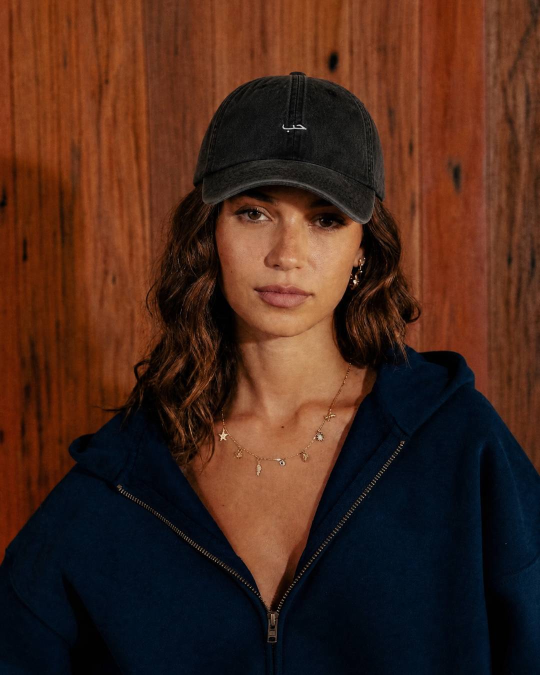 Woman wearing a dark cap and navy jacket against a wooden background