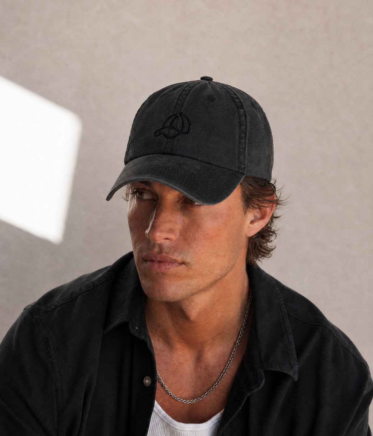 WASHED CAP ON CAP. BLACK worn by a man