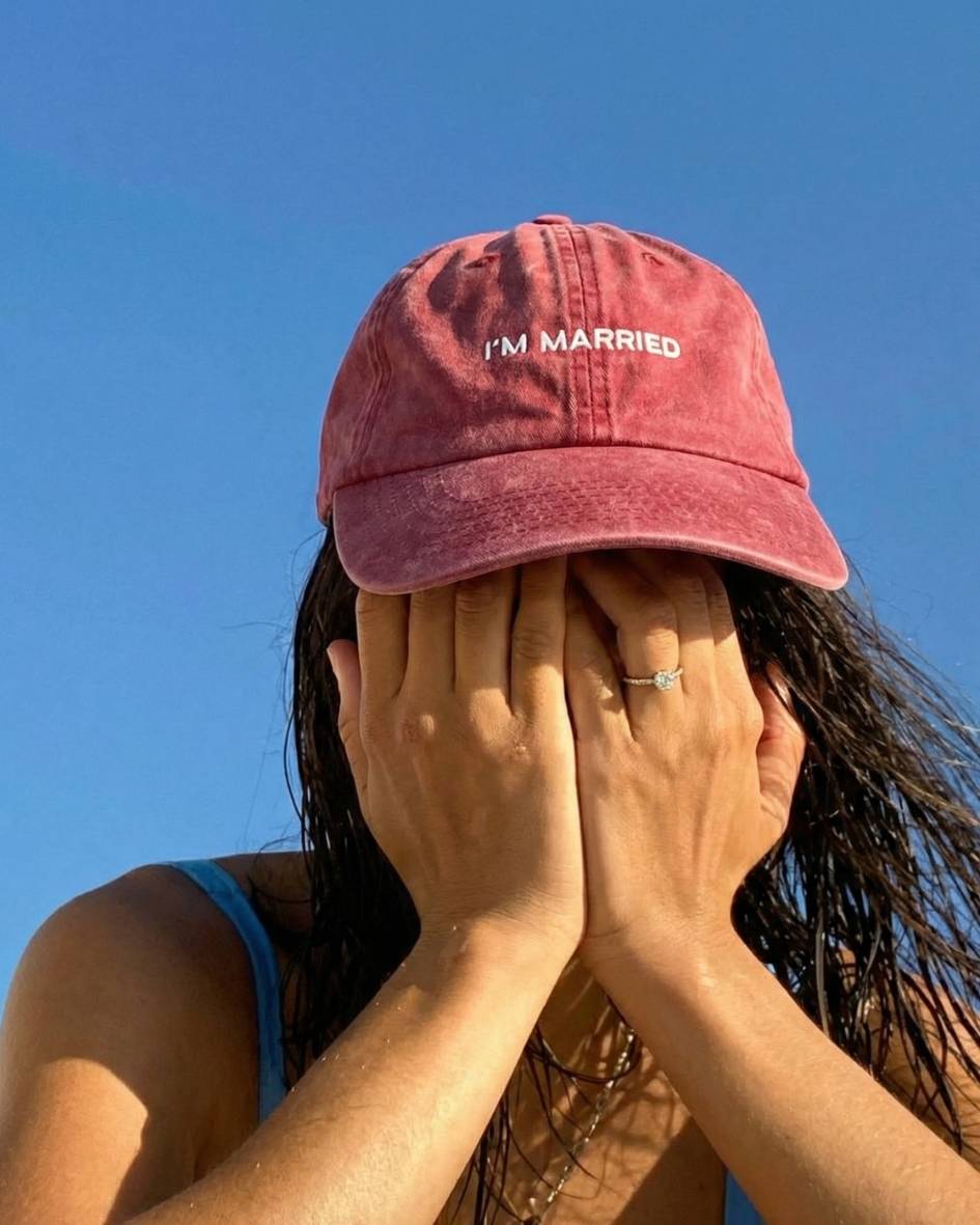 Person wearing a red 'I'm Married' cap against a clear blue sky.