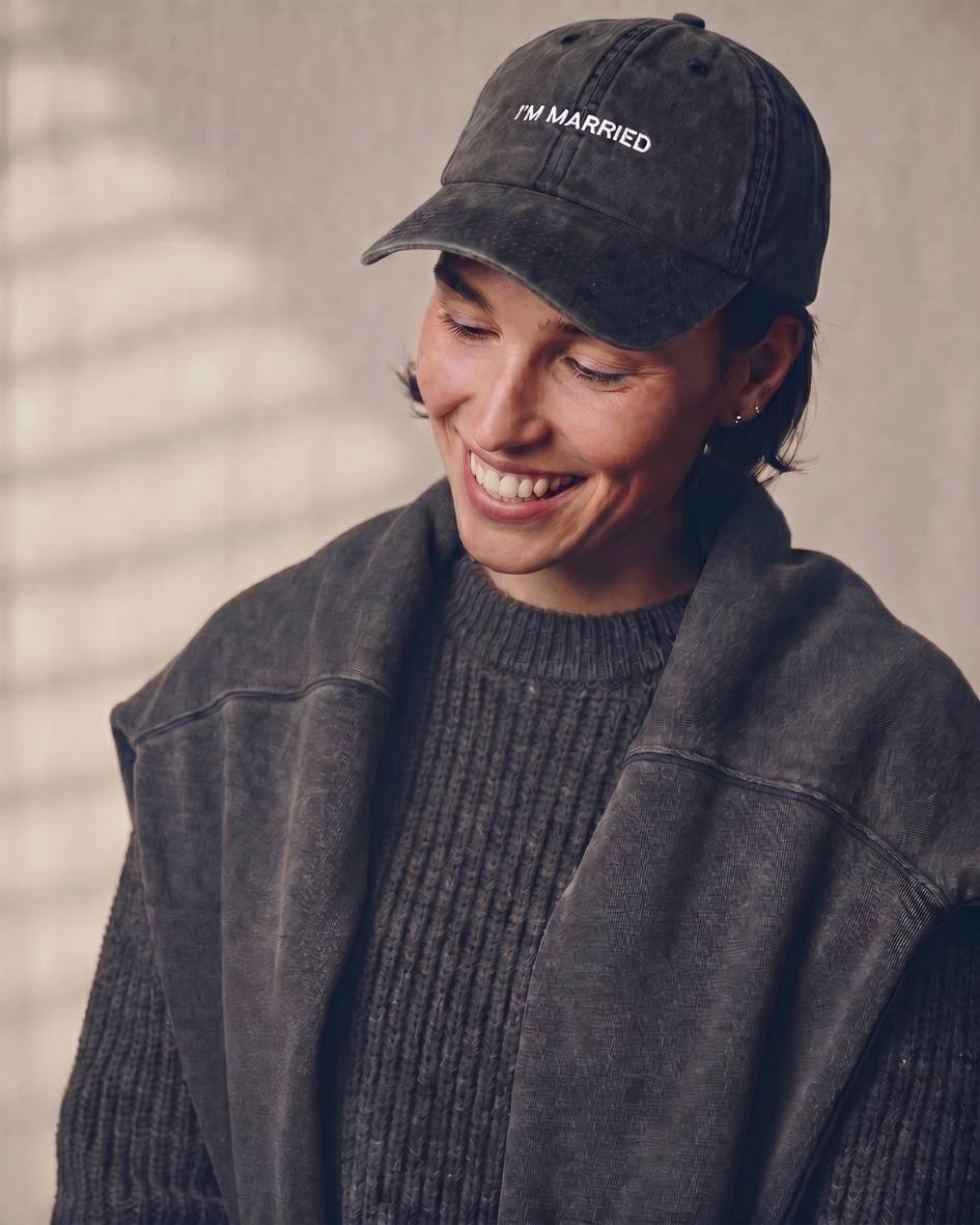 Person wearing a black cap with 'I'm Married' text, smiling against a neutral background