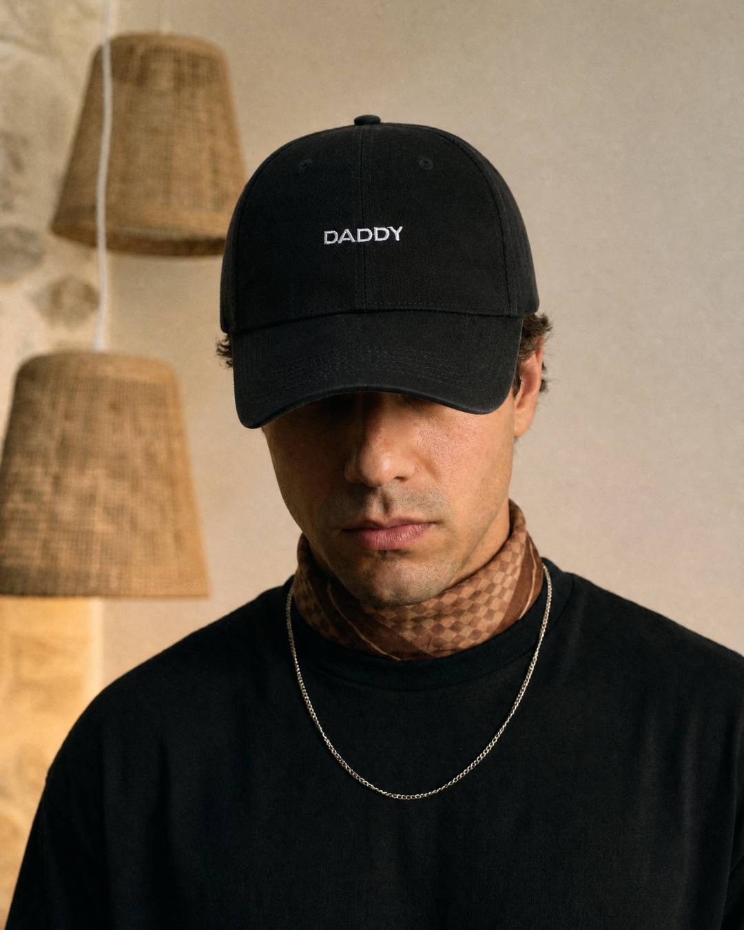 Man wearing a black cap with 'DADDY' text against a neutral background