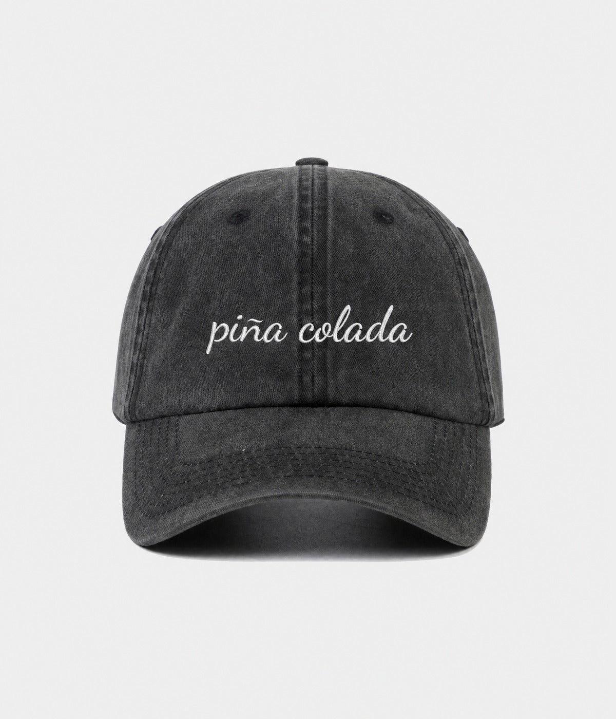 PINA COLADA - CURSIVE. washed black cotton dad cap with embroidered pina colada script, front view