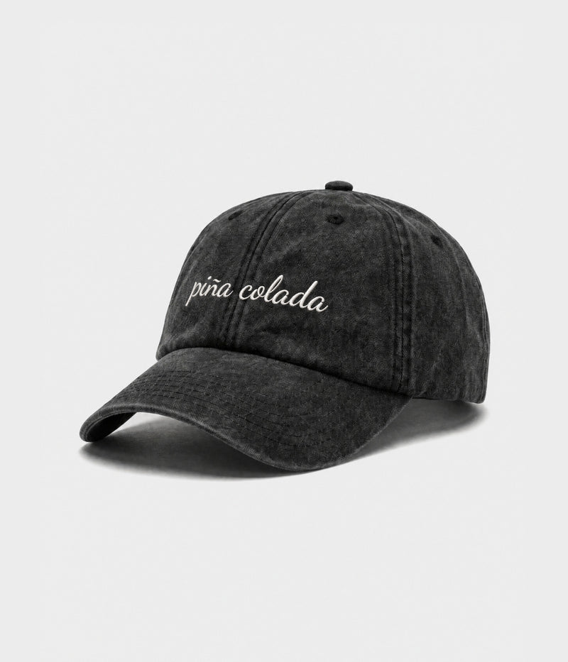 PINA COLADA - CURSIVE. washed black cotton dad cap with embroidered pina colada script, side view