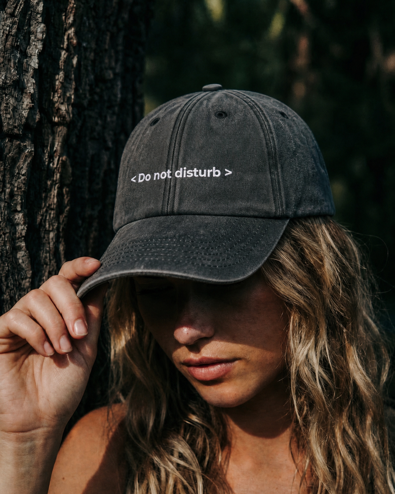 Person wearing a black cap with 'Do not disturb' text in a forest setting