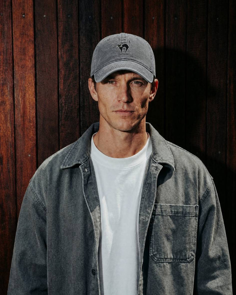 Man wearing a gray cap and denim jacket against a wooden background